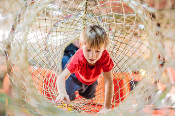 Boy crawls on a net in an obstacle course