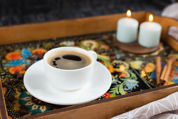 A white cup of coffe staying on a fancy tray with traditional decorative painting style - Ukrainian Petrykivka - on dark wooden background