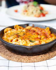 Baked macaroni and cheese with fresh tomato sauce served on hot pan