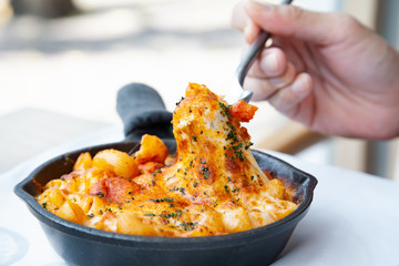Baked macaroni and cheese with fresh tomato sauce served on hot pan