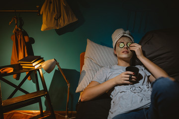 woman with applied cosmetic face mask relaxing in her bedroom