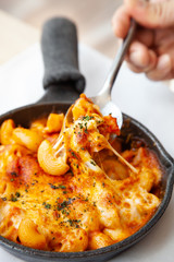 Baked macaroni and cheese with fresh tomato sauce served on hot pan
