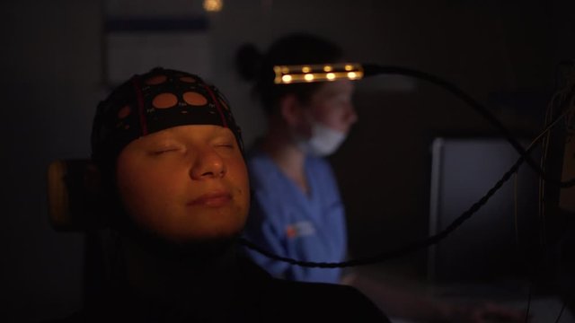 EEG examination of young man. Brain test in a dark office in hospital. Modern methods of diagnostics