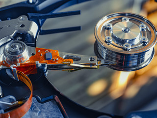 The old IDE hard disk internal components with a beautiful shiny magnetic disk.