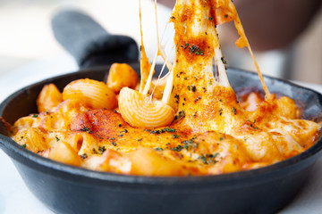 Baked macaroni and cheese with fresh tomato sauce served on hot pan