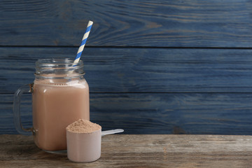 Protein shake and powder on wooden table, space for text