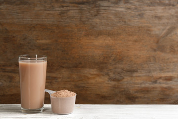 Protein shake and powder on white wooden table, space for text