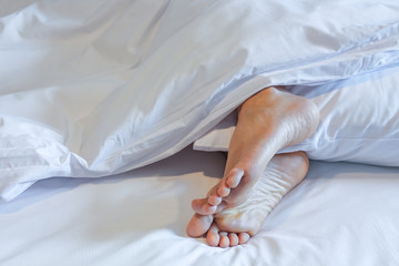 Feet of sleeping woman in white bed room