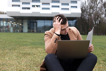 Man sitting with a laptop and depressed because of work. Pensive student holds his head