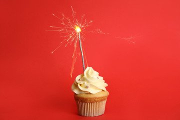 Birthday cupcake with sparkler on red background