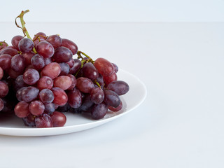 Bunch of grapes on white plate.