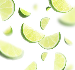 Falling juicy cut limes on white background