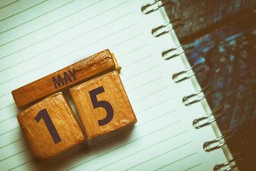 may 15th. Day 15 of month,Handmade wood cube with date month and day placed on a lined notebook on a blue background. artistic coloring.  spring month, day of the year concept