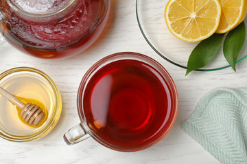 Delicious tea with honey and lemon on white wooden table, flat lay