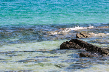 Splash of sea water waves hitting the rocky beach
