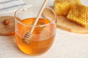 Glass jar of honey on white wooden table, closeup