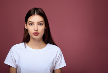 Fototapeta premium A cute girl in a white T-shirt looks straight and confidently.