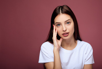 Fototapeta premium The young brunette bowed her head to one side on a pink background.