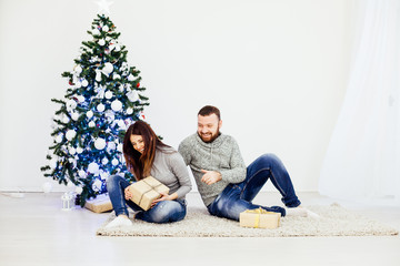 a man and a woman sit at the Christmas tree new year gifts holiday winter