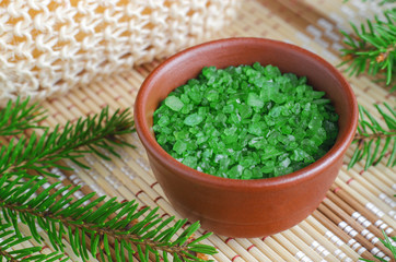  Small bowl with green aroma bath salts and fir tree branches. Christmas aromatherapy. Winter spa and herbal medicine concept. Close up, copy space.