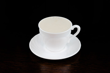 black coffee pour into a white mug on a dark background