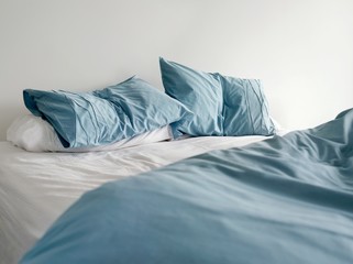 Unmade Bed With Crumpled Blue Bed Linens