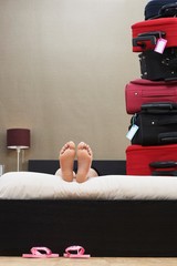 Woman In Bed Next To Stack Of Suitcases
