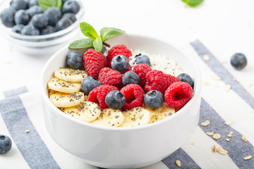 Breakfast smoothie with granola, yogurt, fresh raspberries, blueberries, bananas, coconut flakes, Chia seeds and mint. Healthy food. Breakfast food.