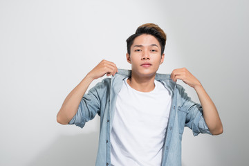 closeup of a young Asian man holding his hands on the collar of his jeans shirt isolated on a white background