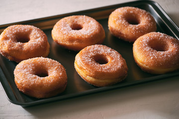 Fried Donuts with Powdered Sugar on metal baking dish