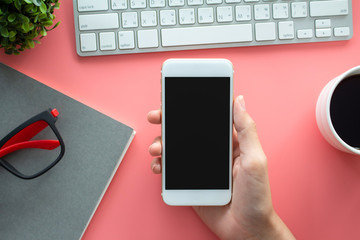 Female hands working use phone  on  modern pink desk office background