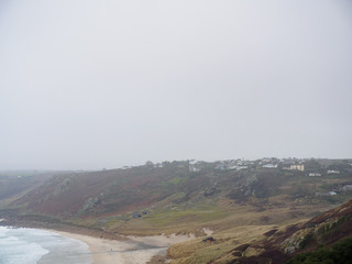 Wide angle view of a small village overlooking the hills along Gwyner Beach on a dark, foggy day. Sennen Cove, Cornwall, United Kingdom. Travel and nature. - 310677572
