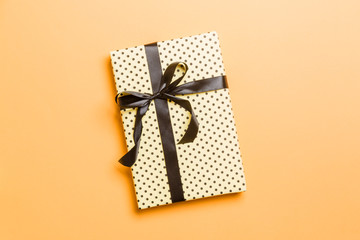 wrapped Christmas or other holiday handmade present in paper with black ribbon on orange...