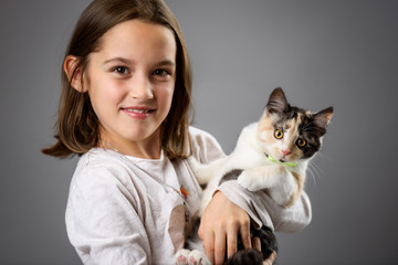 Portrait of happy young little girl with calico kitten cat.