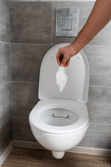 Fototapeta premium Cropped view of man holding napkin above toilet bowl