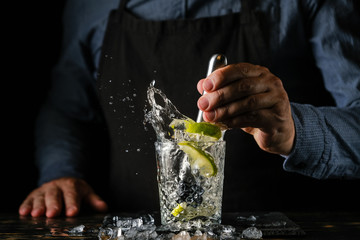 Bartender is preparing a refreshing cocktail with ice and lime. Bartender preparing Caipirinha cocktail. Summer cocktail at the nightclub.