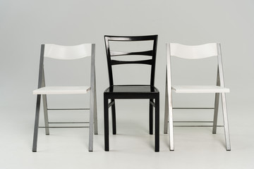 Three black and white chairs on grey background