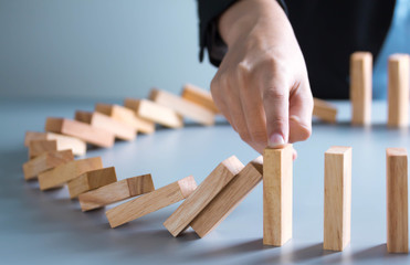 businessman hand stop dominoes continuous toppled or risk with copyspace