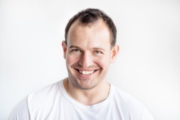 Closeup portrait of smiling 30 years old caucasian white man on white background in white t-shirt. Confident happy smart modern man. Lifestyle. Wide smile with healthy teeth.