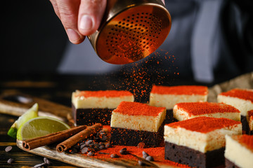 Spiced chocolate cake with cream, on a wooden board with lime and cinnamon stick.