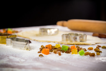 dough on table with dried fruits and cutters
