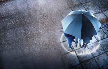Businesspeople Sheltering Under One Umbrella In Rain