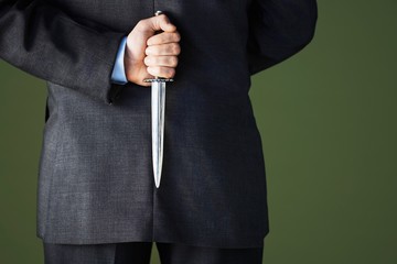 Midsection Of Businessman Holding Knife Behind Back