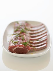 Plate Of Fresh Raw Ribs With Rosemary Sprinkled On It