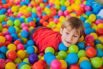 Fototapeta na wymiar Happy little kid boy playing at colorful plastic balls playground high view. Adorable child having fun indoors