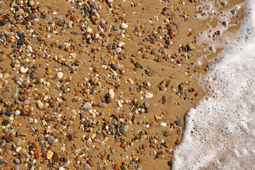 Sand, rocks and foam on resort beach close-up