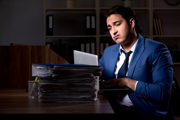 Young male employee working night in the office
