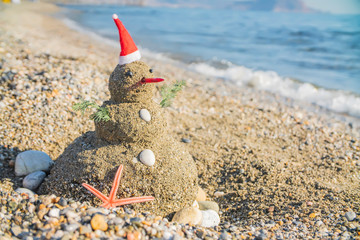  Snowman on holidays made of sand instead of snow. Concept tropical resort could be used for New Year and Christmas