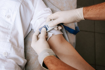 Doctor puts a tourniquet on a patient's arm in a hospital