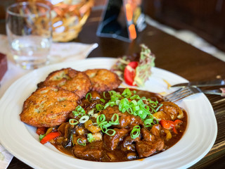 traditional czech goulash dish with fried potatoes & spring onion